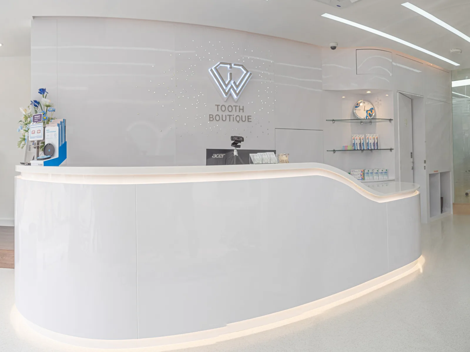 Curved white reception desk with the Tooth Boutique logo on the wall